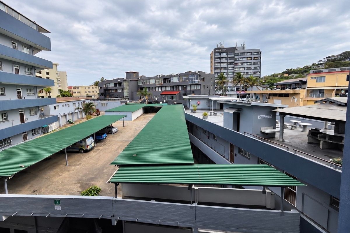Elevated view of the apartment complex rear courtyard featuring covered parking bays and communal outdoor space.