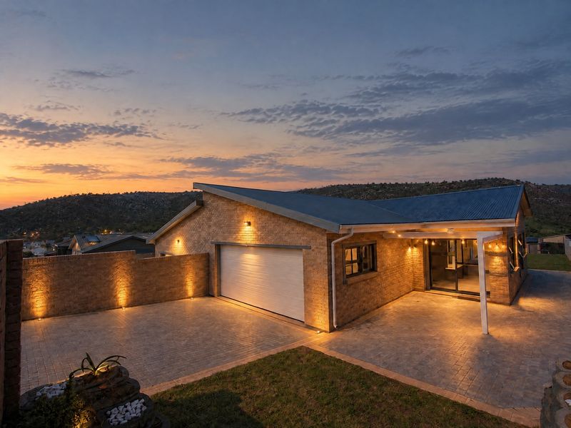 A well-maintained duet property featuring a brick facade, paved driveway, integrated garage, and a covered patio area at dusk.