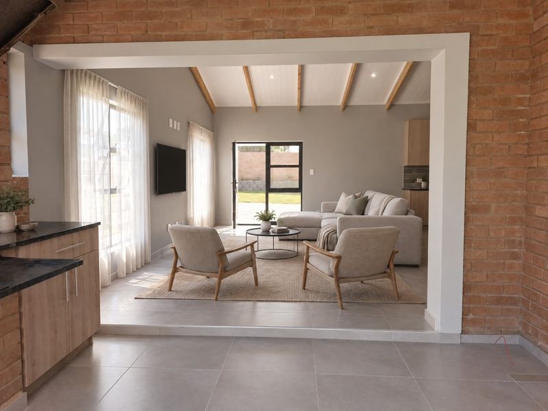 Spacious open-plan living area featuring vaulted ceilings with exposed timber beams, tiled flooring, and direct access to the rear garden through aluminium doors.