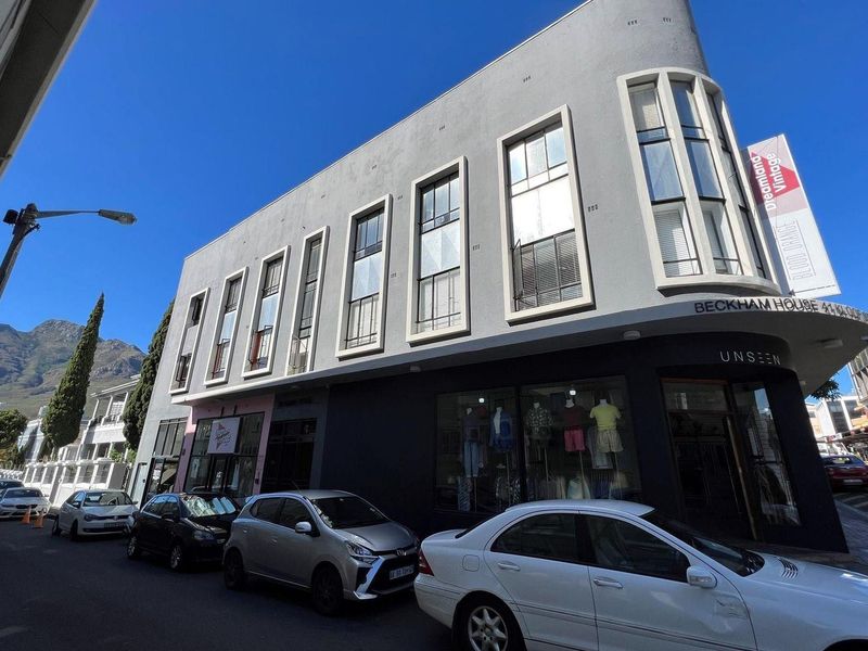 A well-maintained multi-story commercial building featuring a prominent curved corner facade and large street-level display windows in a busy urban setting.