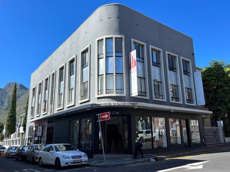 A prominent corner commercial building, Beckham House, featuring large display windows and a modern grey facade located on a street corner.