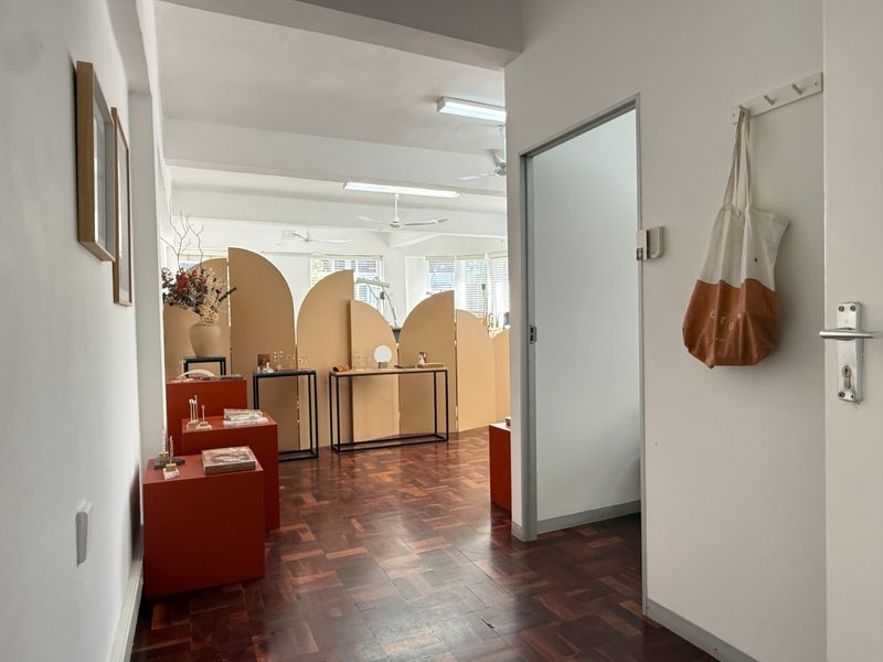 Open plan commercial space featuring classic parquet flooring, functional ceiling lighting, and ceiling fans, providing a versatile layout for various business operations.