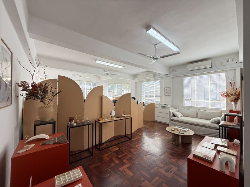A bright commercial office space featuring classic parquet flooring, ceiling fans, and split system air conditioning, offering a versatile layout for professional use.