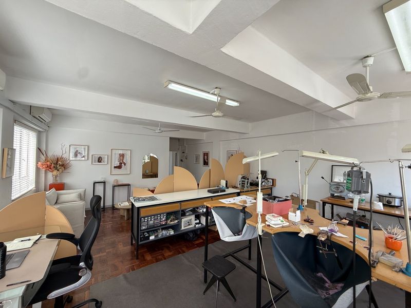 Spacious commercial office area featuring parquet flooring, ceiling fans, and integrated air conditioning, suitable for a creative studio or workshop environment.