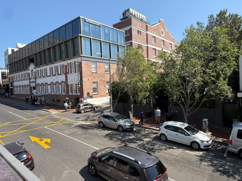 Street-level view of a commercial building featuring a mix of traditional brick architecture and a modern glass-fronted upper level.