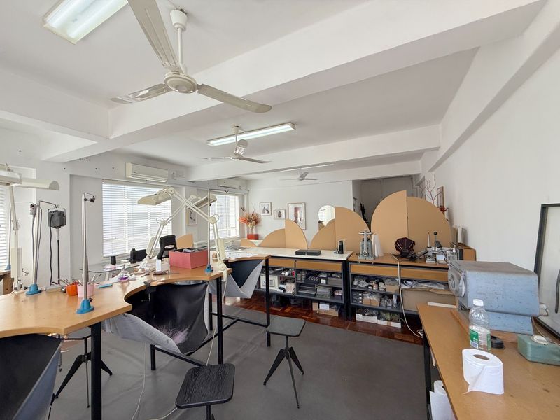 A functional commercial office space featuring parquet flooring, ceiling fans, split-system air conditioning, and large windows with venetian blinds.