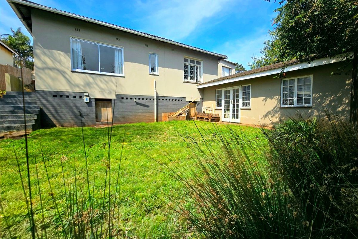Rear view of the house featuring a lawn, concrete stairs, and a mix of sliding and french door access points.