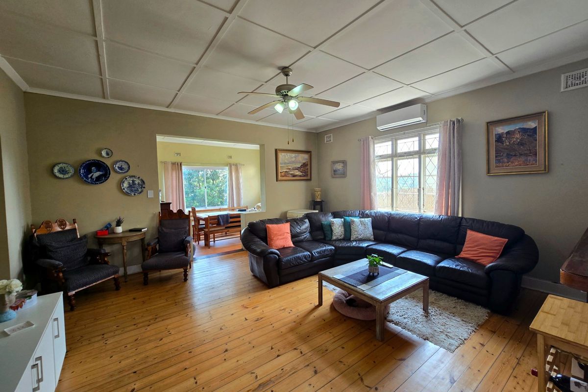 Spacious living room featuring polished timber flooring, a ceiling fan, and a split system air conditioner, with an adjoining dining area visible.