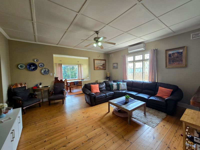 Spacious living room featuring polished timber flooring, a ceiling fan, and a split system air conditioner, with an adjoining dining area visible.