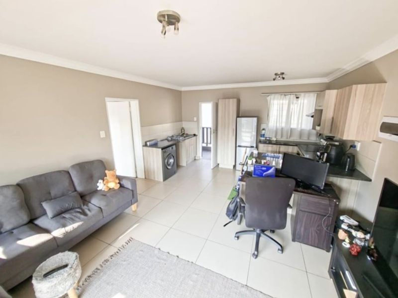 Open-plan living area featuring tiled flooring, coved ceilings, and a functional kitchen with built-in cabinetry and integrated appliances.