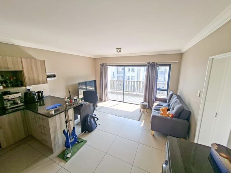 Open-plan living area featuring a modern kitchen with granite countertops, tiled flooring, and large sliding doors leading to a private balcony.