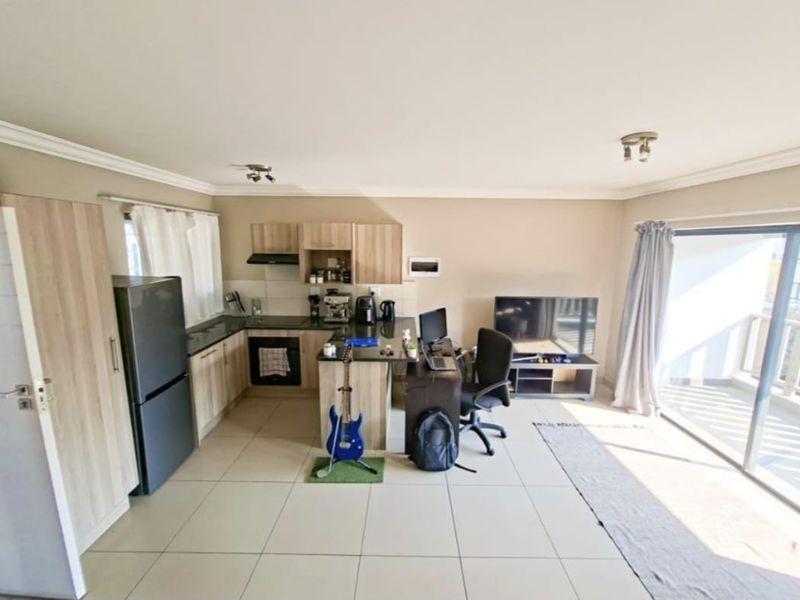 Open-plan living area featuring a modern kitchen with granite countertops, built-in cabinetry, and direct access to a balcony through sliding glass doors.