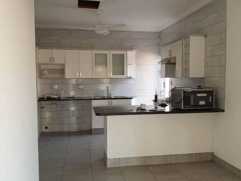 A functional kitchen featuring built-in cabinetry, granite countertops, and a tiled backsplash. The space includes a breakfast bar and requires minor ceiling repairs.