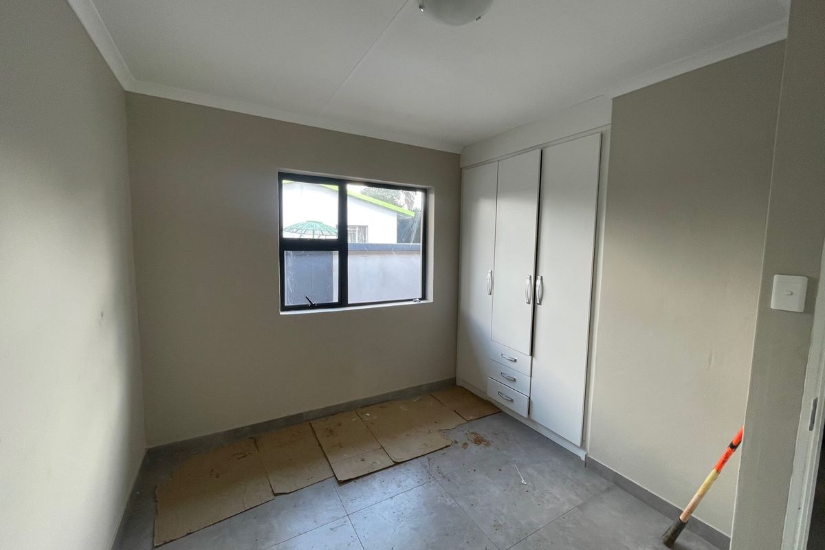 A vacant bedroom featuring neutral wall paint, tiled flooring, and a built-in wardrobe with integrated drawers.