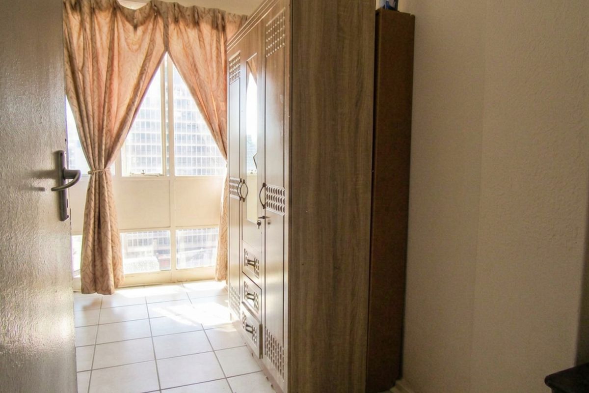 A bedroom featuring tiled flooring and a large window that allows for natural light.