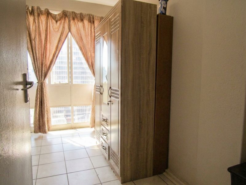 A bedroom featuring tiled flooring and a large window that allows for natural light.