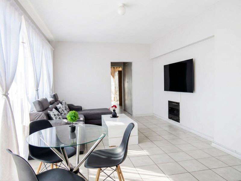 Bright open-plan living area featuring neutral tiled flooring and a built-in fireplace, offering a clean and versatile space for relaxation and dining.