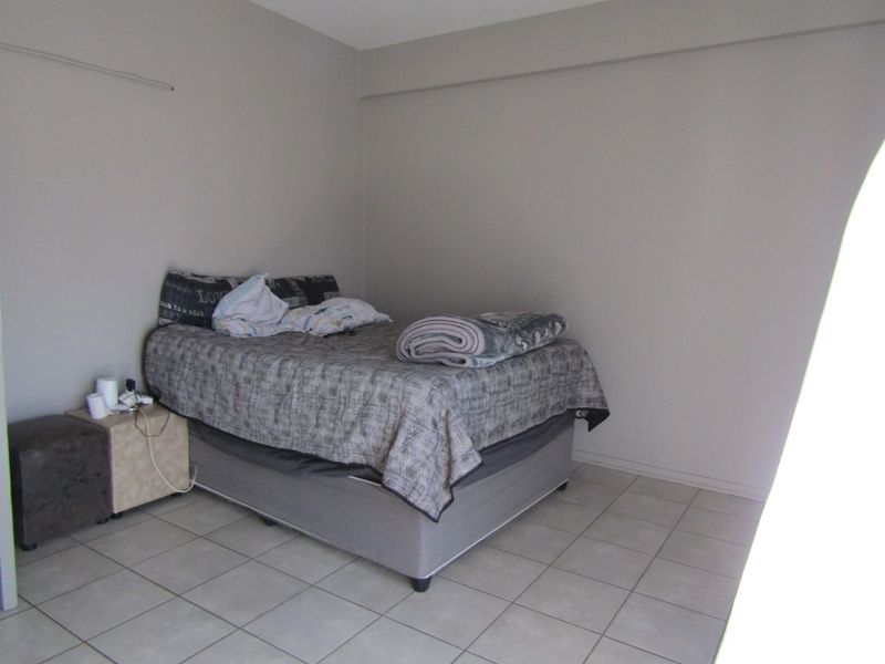 A simple bedroom featuring neutral wall paint and tiled flooring, providing a functional and blank canvas for potential interior design updates.