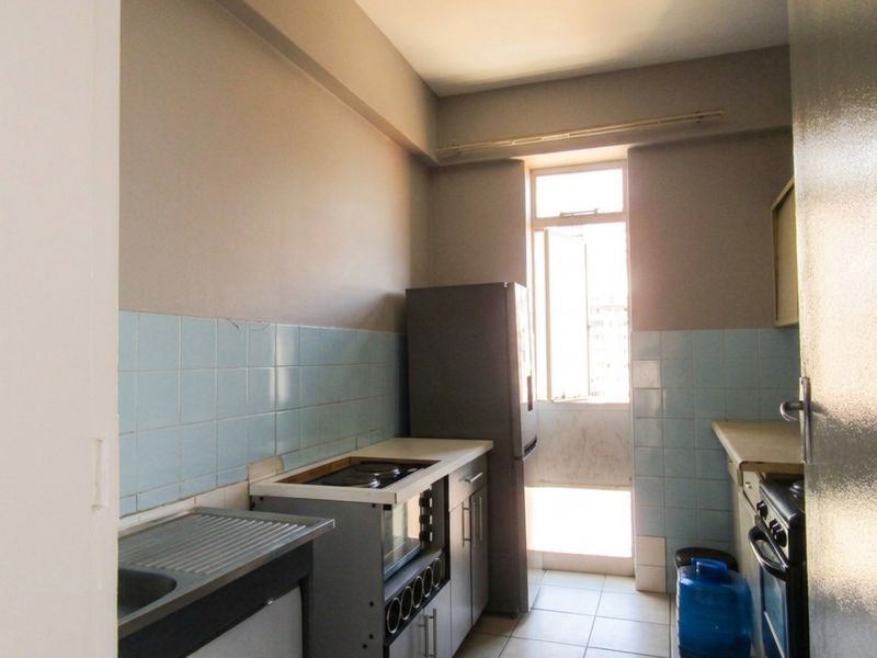A functional kitchen featuring tiled splashbacks, built-in cabinetry, and a freestanding stove, offering a practical layout with natural light from the adjacent window.