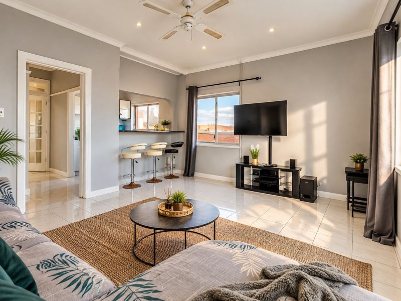 Bright and spacious living room featuring tiled flooring, recessed downlights, a ceiling fan, and a convenient breakfast bar pass-through to the kitchen area.