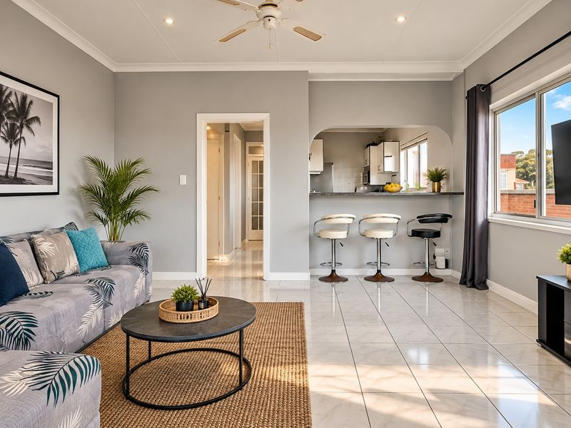 Open plan living area featuring tiled floors, a ceiling fan, and a breakfast bar pass-through connecting to the kitchen.