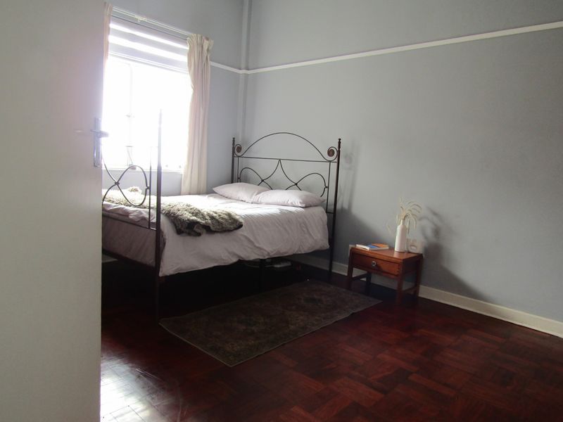 A bedroom featuring classic parquet flooring, a picture rail, and a window allowing natural light.