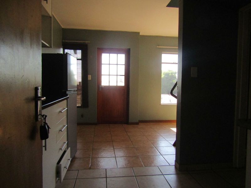 A kitchen area featuring tiled flooring, built-in cabinetry, and a timber-framed exterior door leading to the outside.