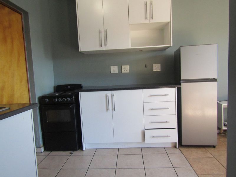 A functional kitchen area featuring white cabinetry, dark countertops, ceramic floor tiling, and a built-in stove, providing a practical workspace.
