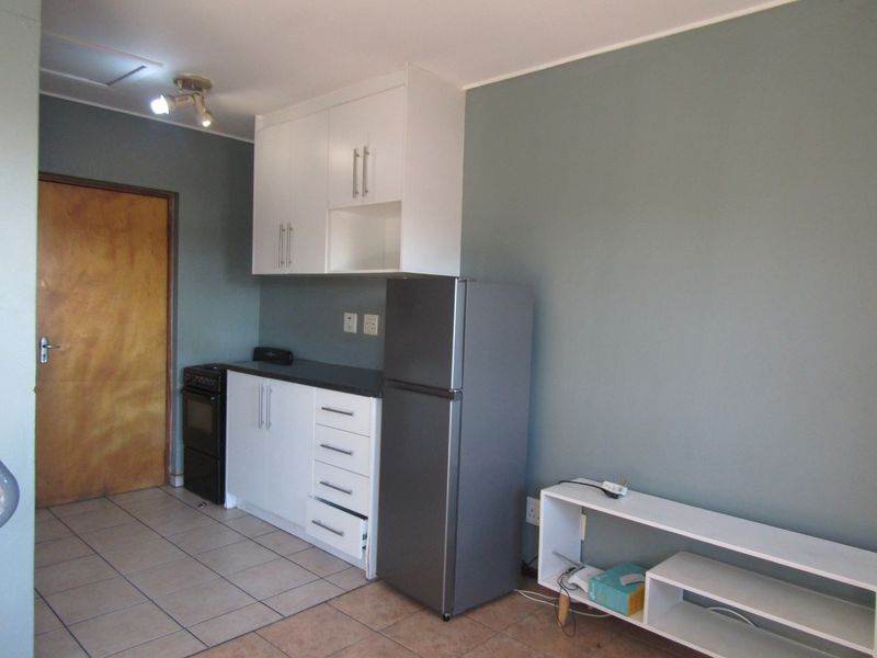 Open plan kitchen area featuring white cabinetry, dark countertops, tiled flooring, and a neutral wall finish.
