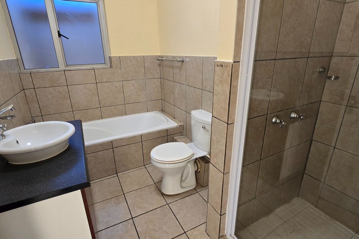 A functional bathroom featuring a built-in vanity with vessel sink, separate bathtub, toilet, and a tiled shower enclosure.