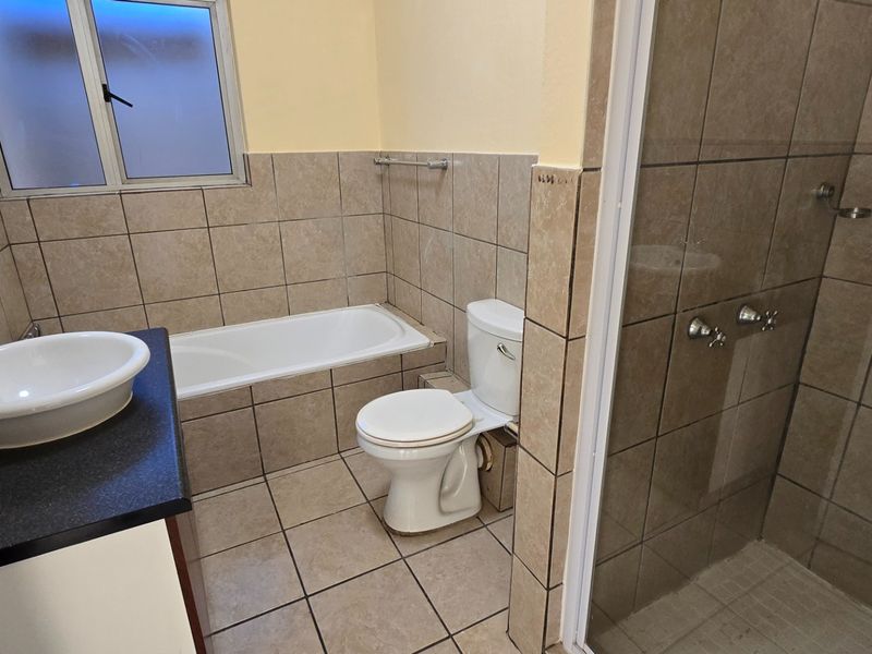 A functional bathroom featuring a built-in vanity with vessel sink, separate bathtub, toilet, and a tiled shower enclosure.