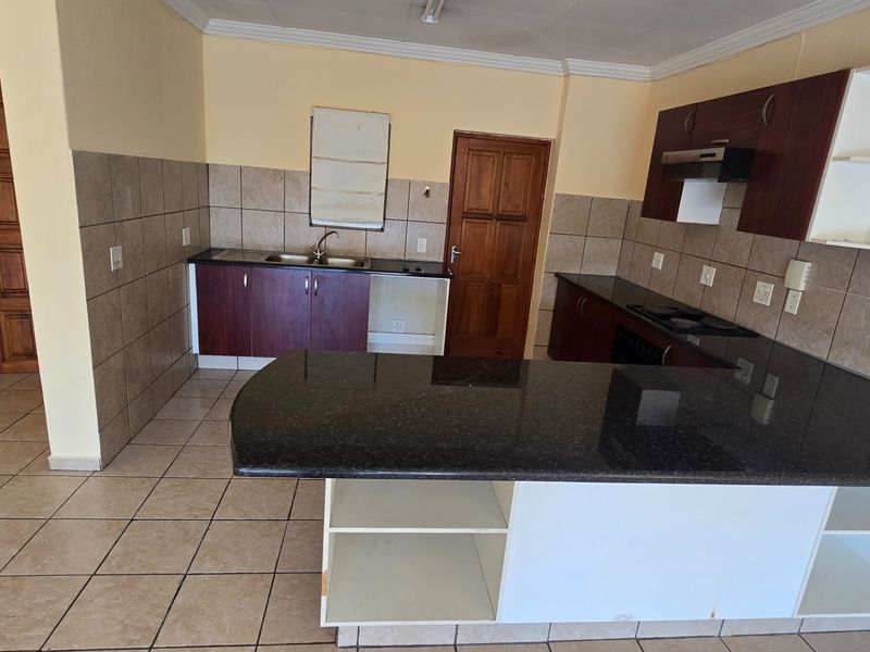A functional kitchen featuring granite countertops, built-in cabinetry, a breakfast bar, and tiled flooring, offering a practical layout ready for updates.