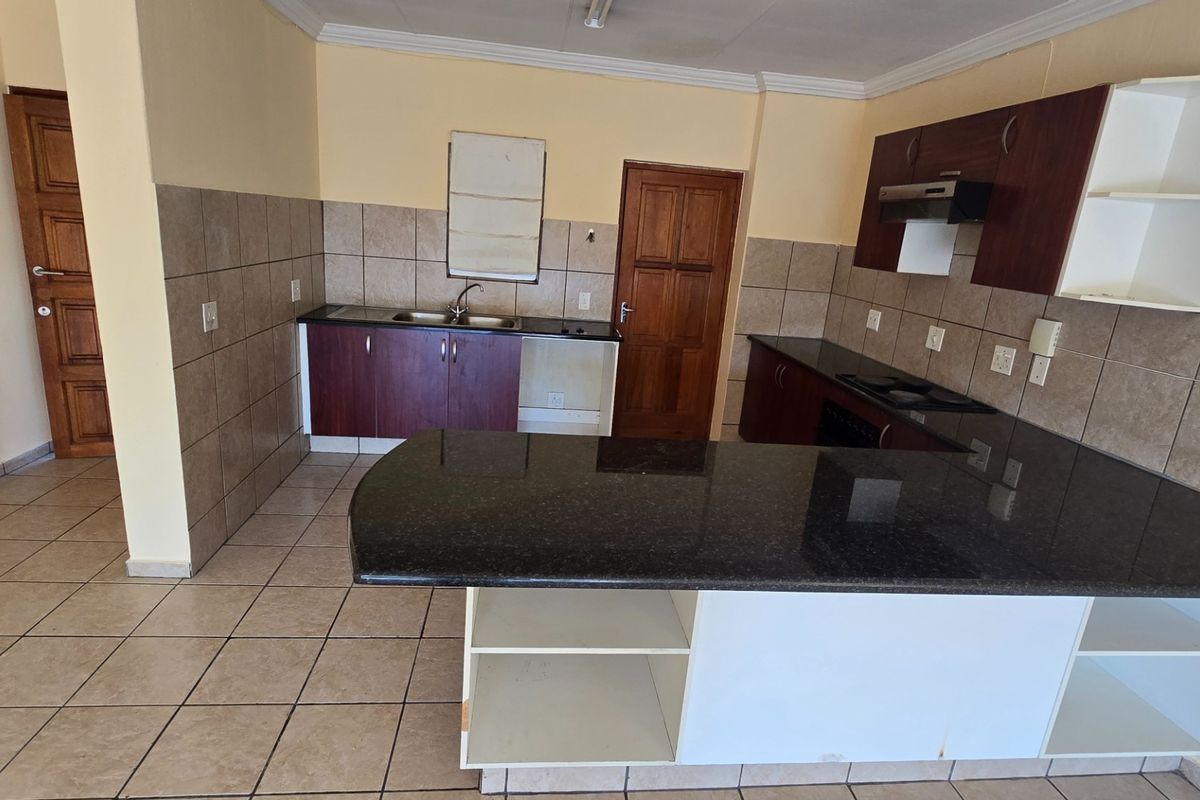 A functional kitchen featuring granite countertops, built-in cabinetry, a breakfast bar, and tiled flooring, offering a practical layout ready for updates.