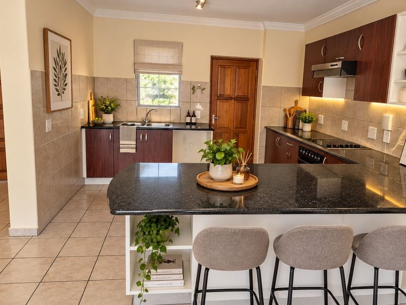 A well-maintained kitchen featuring dark wood cabinetry, granite countertops, a central island with breakfast bar seating, and integrated cooking appliances.