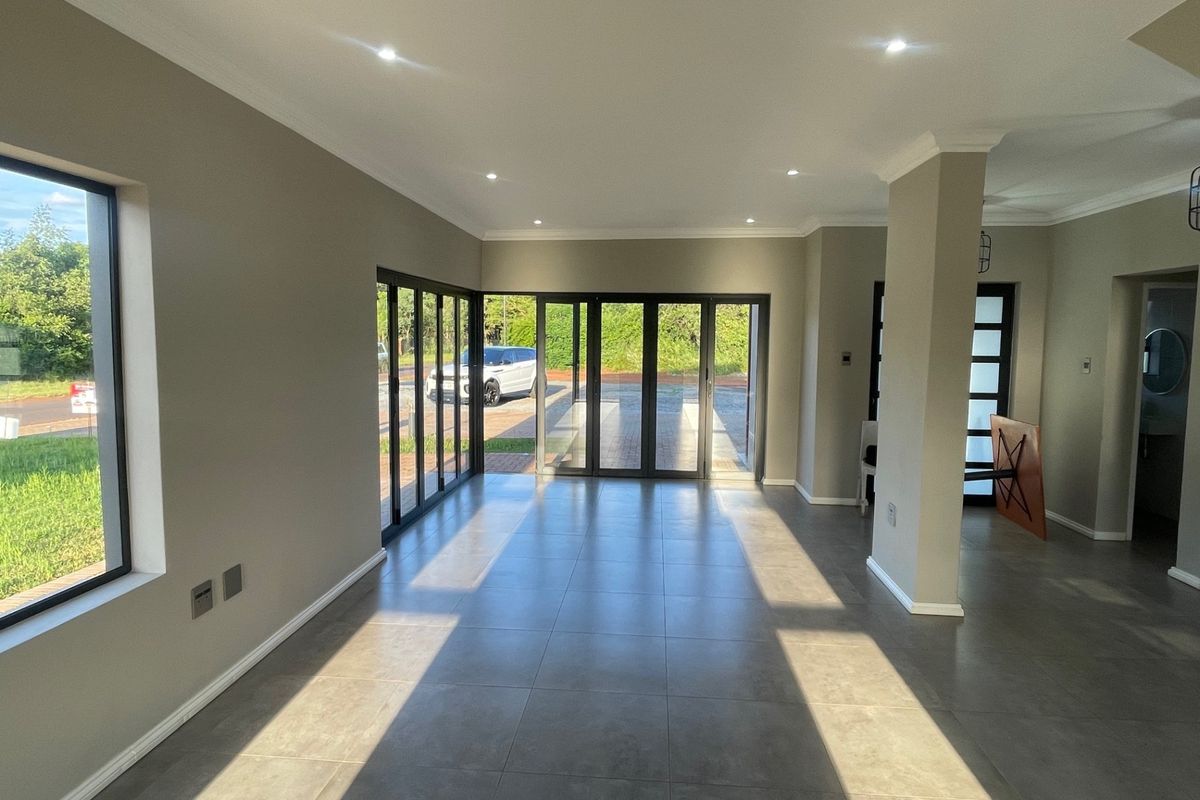 Spacious open-plan living area featuring large format floor tiles, recessed downlighting, and expansive aluminium stacker doors providing seamless access to the exterior.