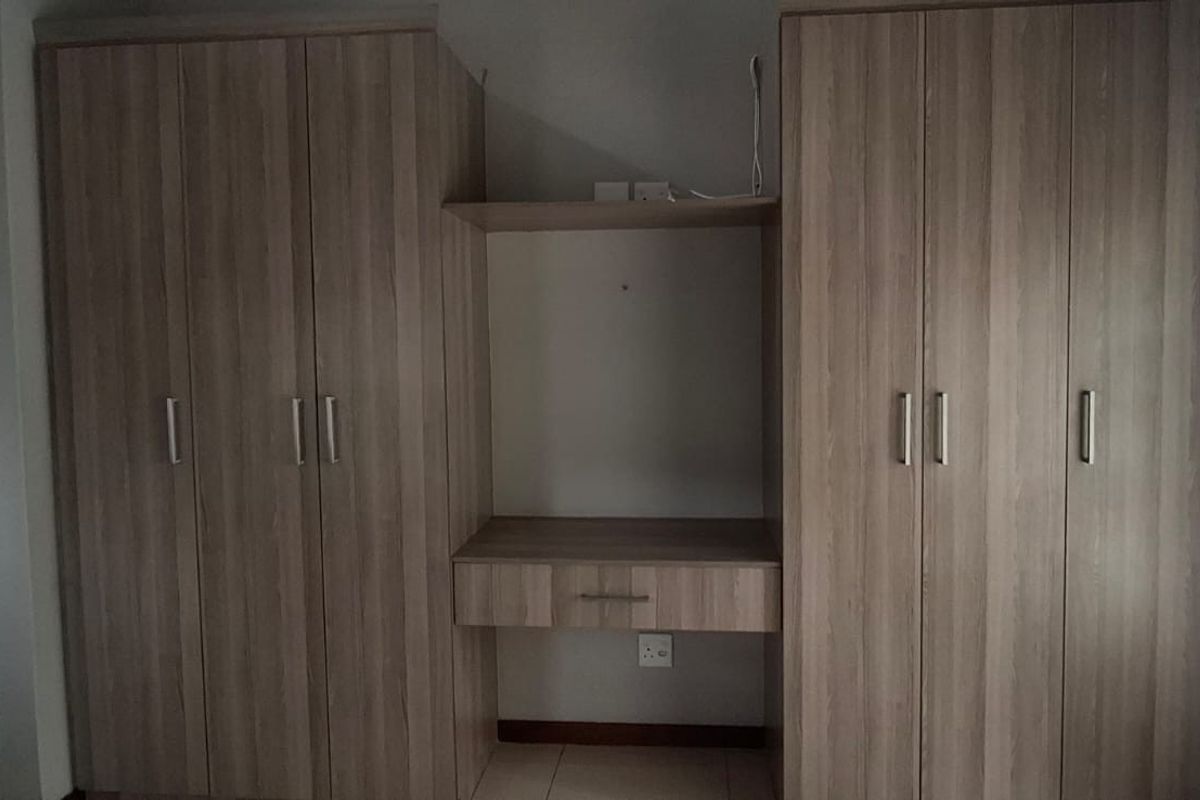 A bedroom featuring extensive built-in wooden cabinetry with a central vanity area and tiled flooring.