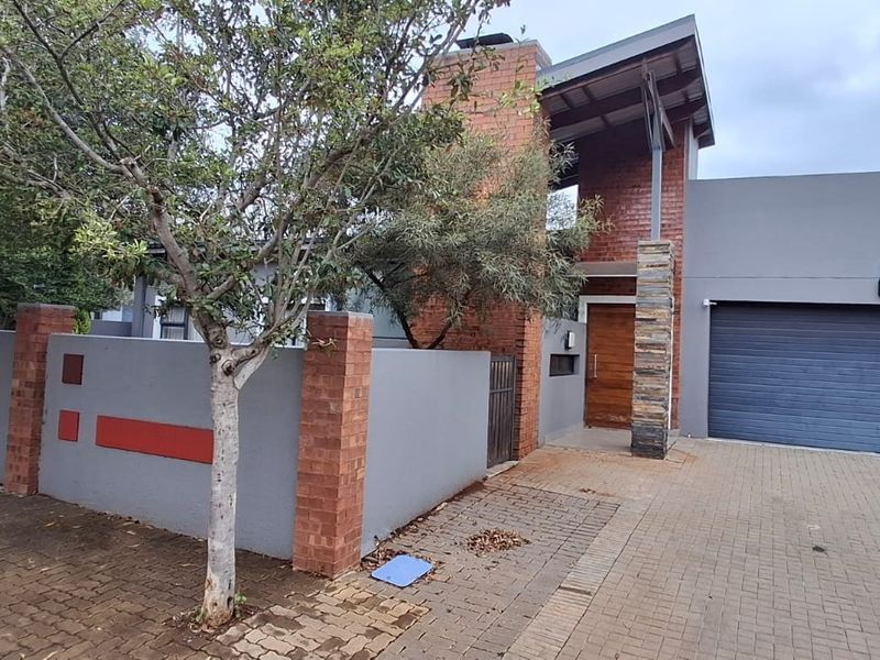Modern front facade featuring a combination of brick and rendered finishes, a paved driveway, and a secure double garage entrance.