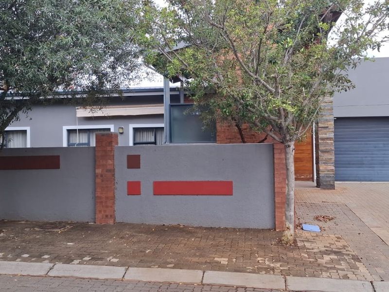 Front view of the property featuring a modern boundary wall with brick accents, a paved driveway, and an integrated garage.
