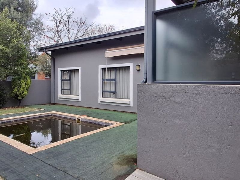 Rear exterior view featuring a small swimming pool, paved surround, and artificial grass area adjacent to the main house structure.
