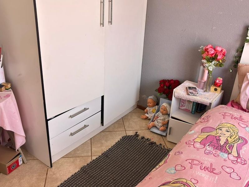 A bedroom featuring a built-in wardrobe and ceramic floor tiles, providing a functional space with neutral wall finishes.