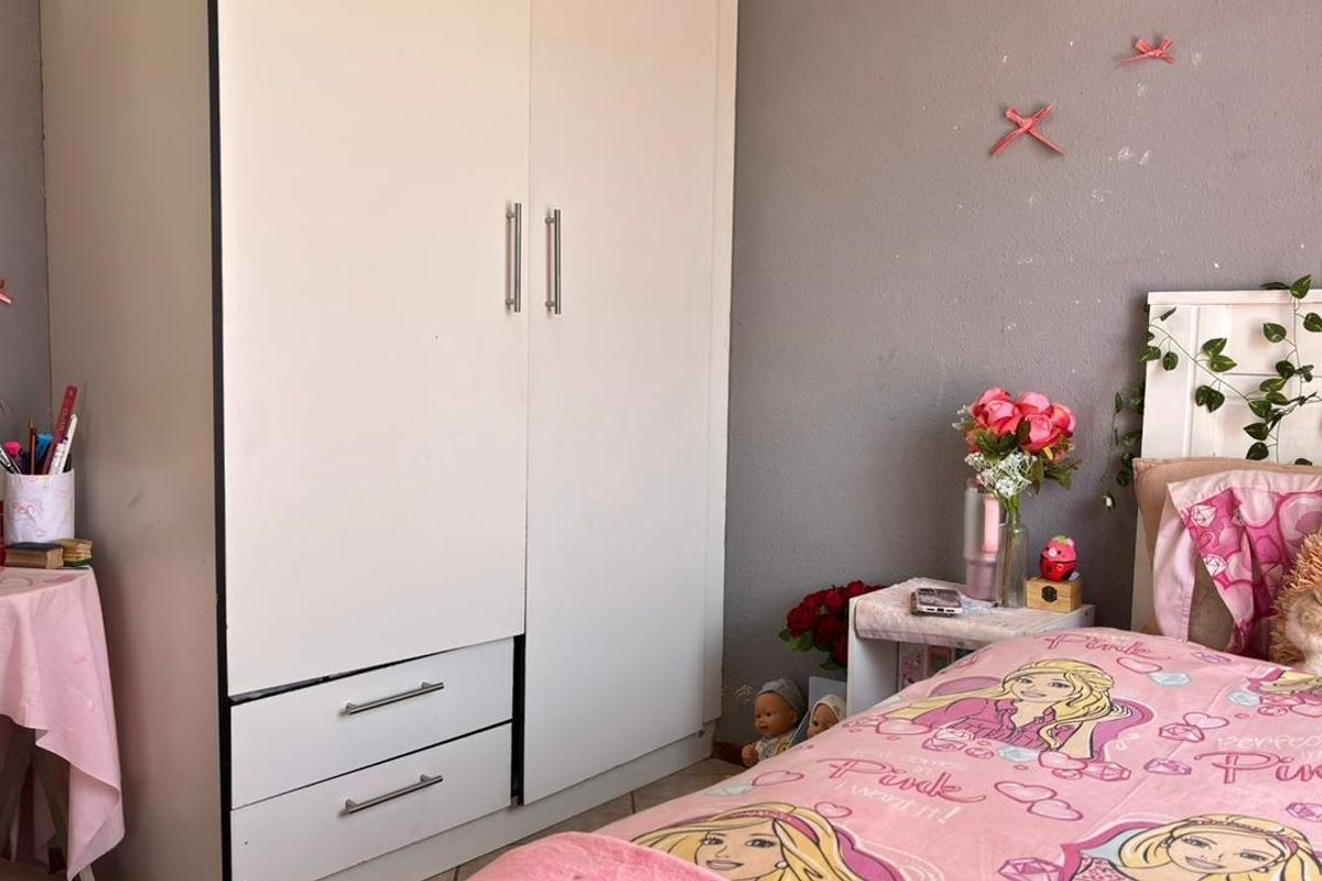 A bedroom featuring a white built-in wardrobe and grey painted walls.