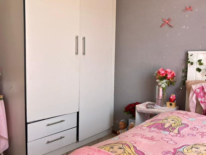 A bedroom featuring a white built-in wardrobe and grey painted walls.