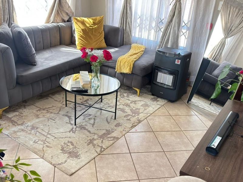 A cozy living room area featuring tiled flooring and a security gate, providing a functional and comfortable space for relaxation.