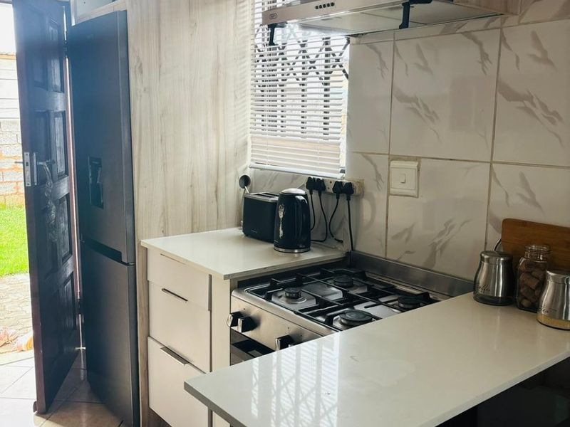 Compact kitchen featuring modern cabinetry, a gas hob with extractor fan, tiled backsplash, and direct access to the exterior.