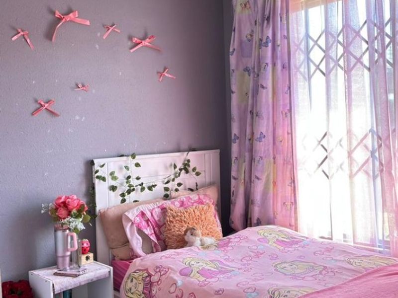 A bedroom featuring tiled flooring, a window with a security gate, and a ceiling light fixture.