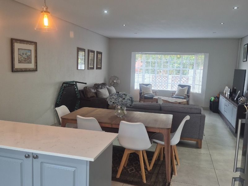 Spacious open-plan living and dining area featuring tiled floors, recessed lighting, and a modern kitchen island with quartz countertops.