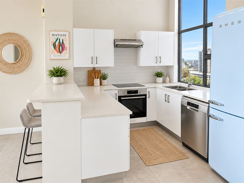 Modern kitchen featuring white cabinetry, stone benchtops, subway tile splashback, integrated appliances, and a breakfast bar with city views.