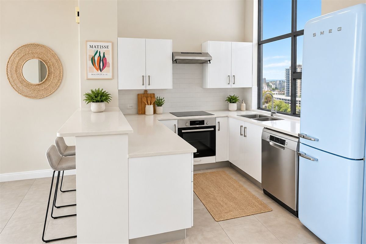 Modern kitchen featuring white cabinetry, stone benchtops, subway tile splashback, integrated appliances, and a breakfast bar with city views.