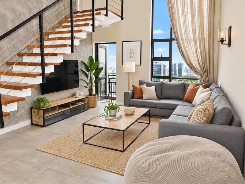 Modern double-volume living area featuring a striking floating staircase, large floor-to-ceiling windows with city views, and contemporary tiled flooring.