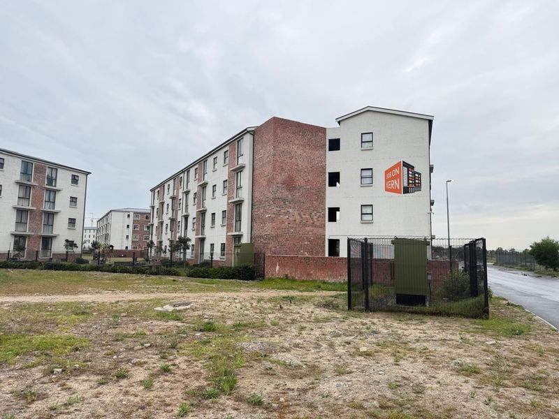 Exterior view of a multi-story apartment complex featuring a combination of brick and plastered facade finishes with surrounding perimeter fencing.